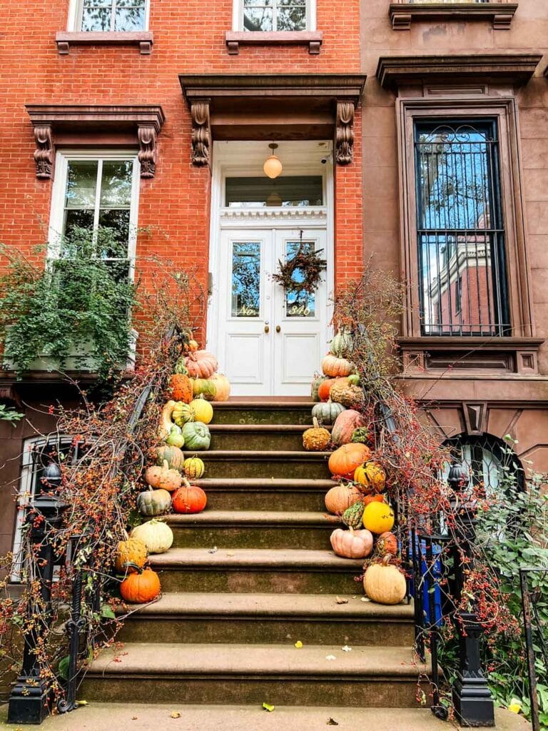 Red brick building, white door, pumpkins on stoop.