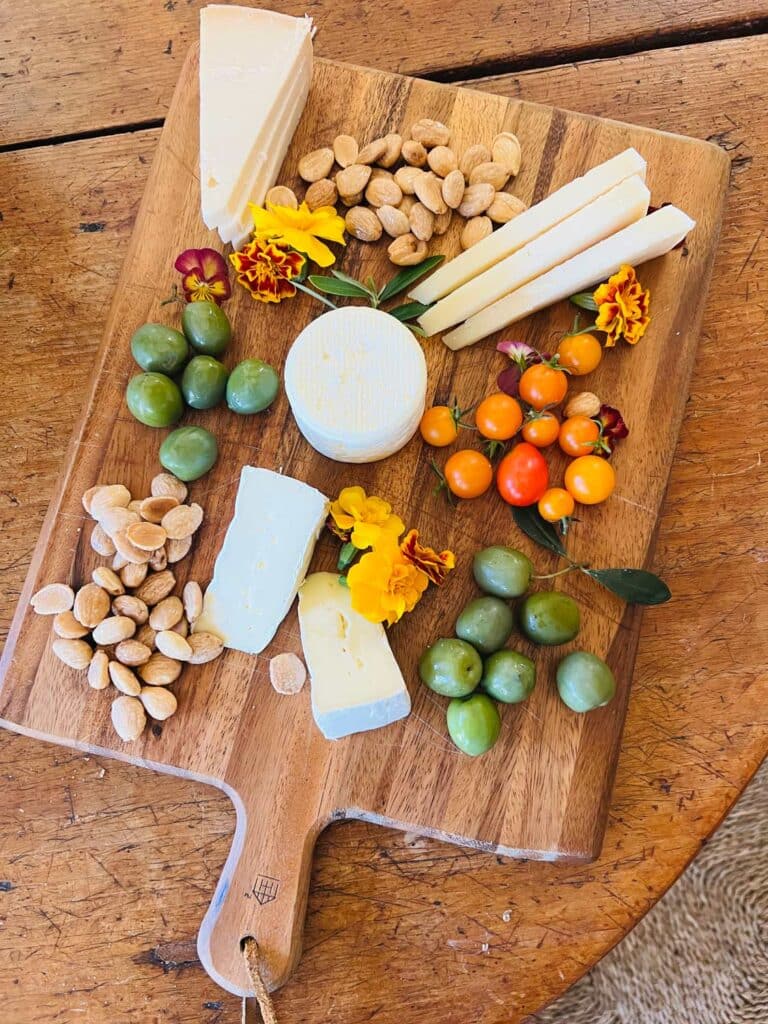 cheese board with olives, cheeses, marigolds 