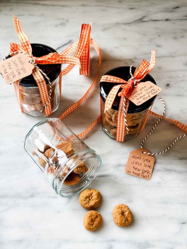 Jars with tiny snickerdoodle cookies and tied up with orange and white gingham ribbon and a tag that says "don't you just love new york in the fall".