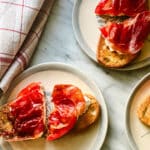 Burrata, tomato and prosciutto tartines are server on small blue and white plates. Make this today.
