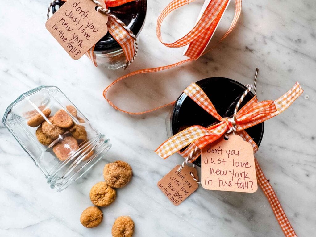 Jars with tiny snickerdoodle cookies and tied up with orange and white gingham ribbon and a tag that says "don't you just love new york in the fall".