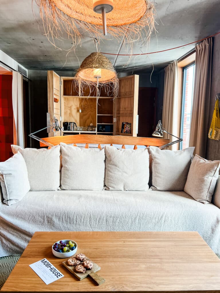 A coffee table with fruit and chocolate chip cookies in front of the sofa in a guest room at the Mob House Hotel Paris.