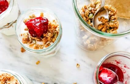 jars with pumpkin granola and yogurt, topped with cranberry sauce