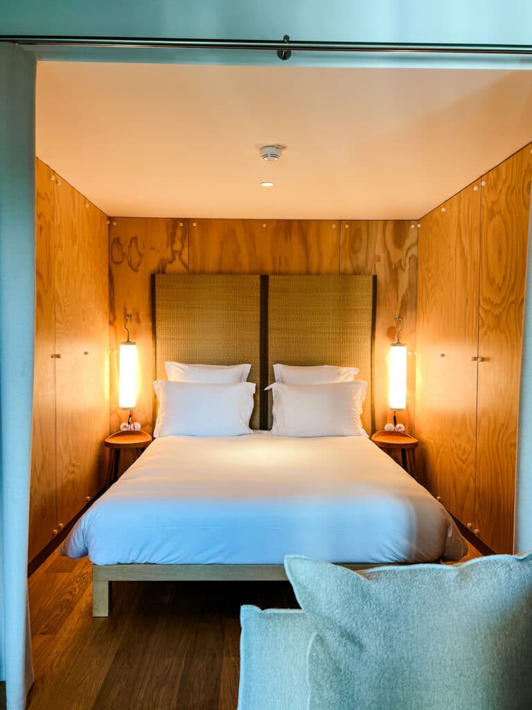 Wood paneled walls adorn this sleeping nook with a queen=sized bed and white linens.