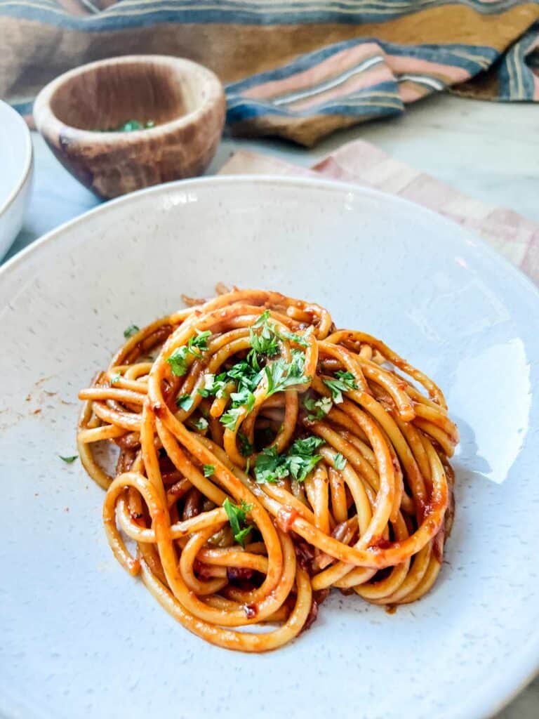 A while bowl of caramelized shallot pasta with chopped parsley, salt, and minced garlic.