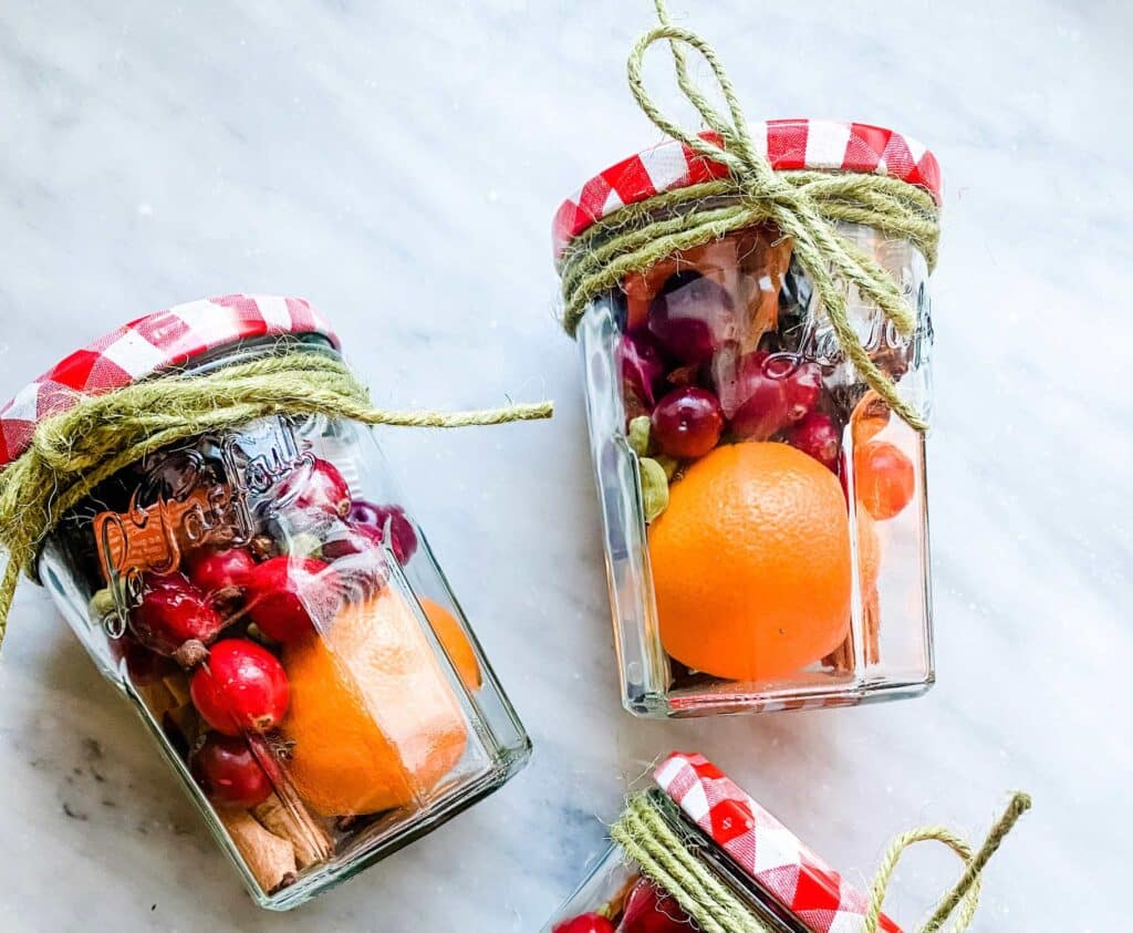Christmas stove top potpourri ingredients are in La Parfait jars with red-checked lids and wrapped with twine.