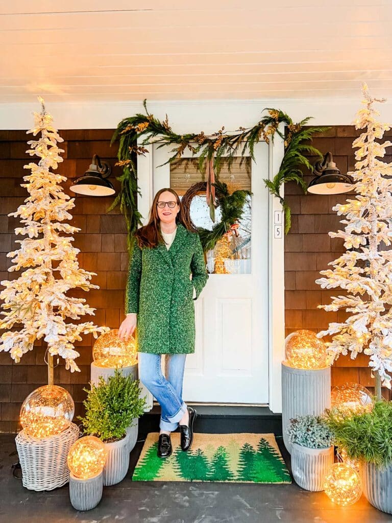 Annie Diamond of mostlovelythings.com standing in front of her door on the porch decorated for the holidays.