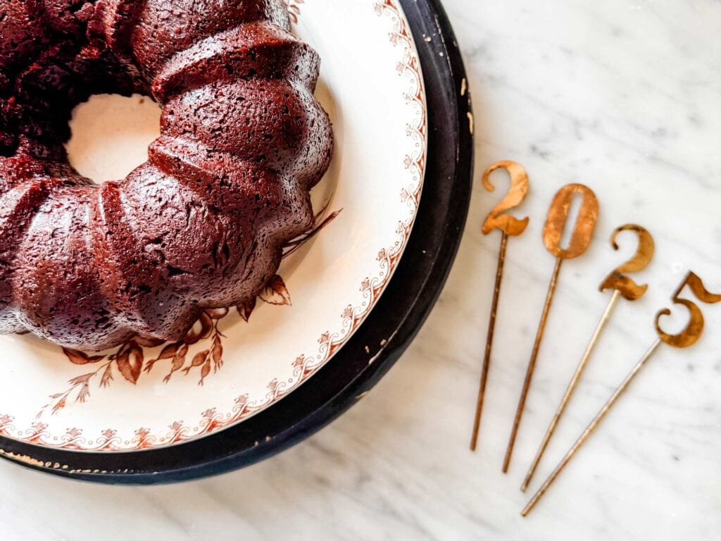 A hot chocolate bundt cake is on a large plate. Next to the plate are the numbers 2025.