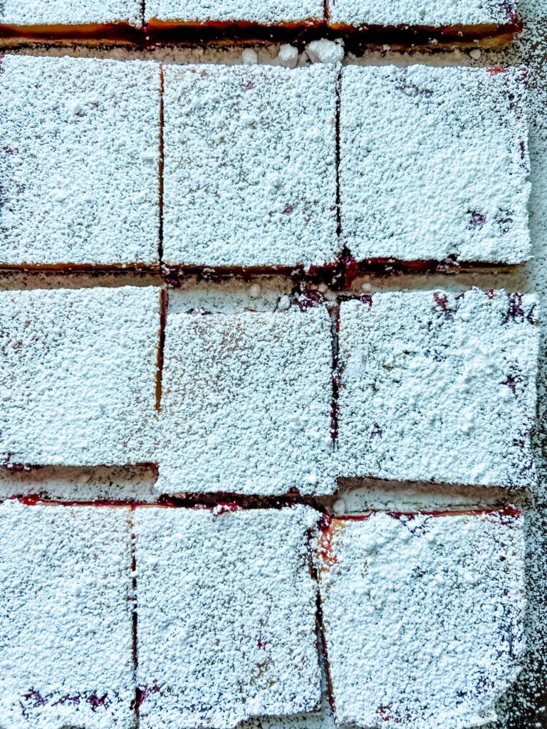 Cranberry and lemon bar squares have been topped with confectioners' sugar and cut into individual squares.
