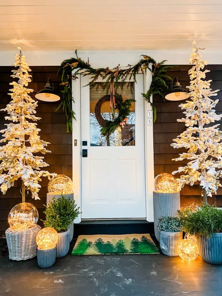 Two white Christmas trees with lights are surrounded by large globes filled with small lights giving off a magical glow for the holiday season.
