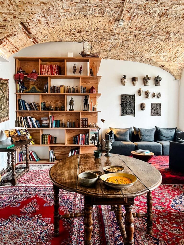 table with bowls, book shelves, art, red rugs 