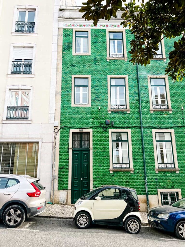 You can find tiles everywhere in Lisbon. This building is covered with bright green tile. A small SmartCar sits out front.