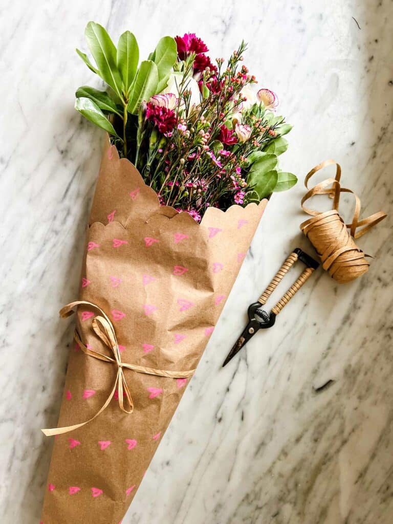 flowers in Kraft paper, raffia, clippers on marble countertop