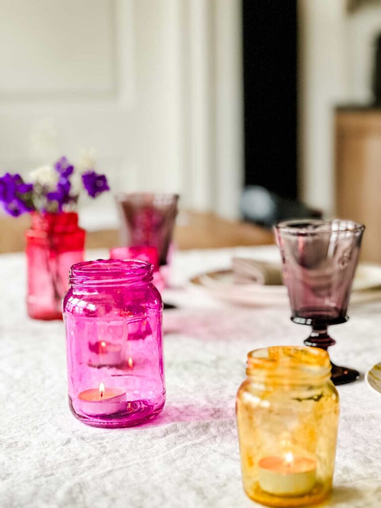Colored glass jars are used for votives on table set for a Valentine's Day brunch.