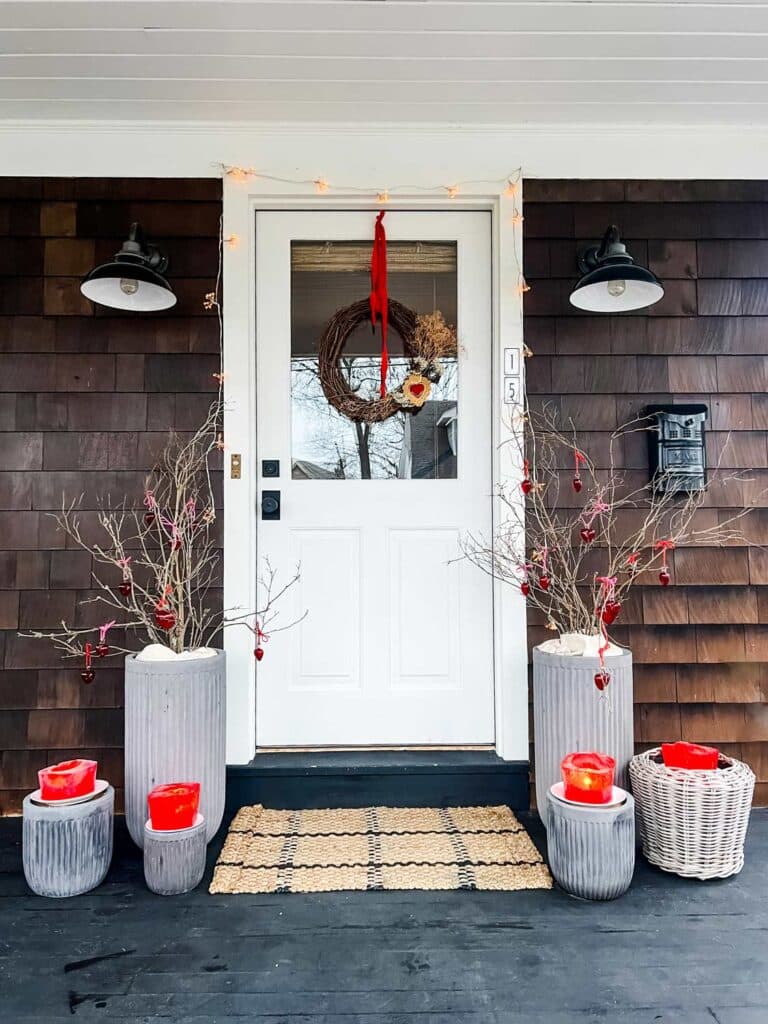 bare branches in our outdoor planters and hung red glass hearts using pink and red twine. White door, lights on each side, door mat, mailbox 