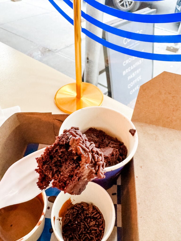 A brownie bite dipped in chocolate sauce and chocolate sprinkles.