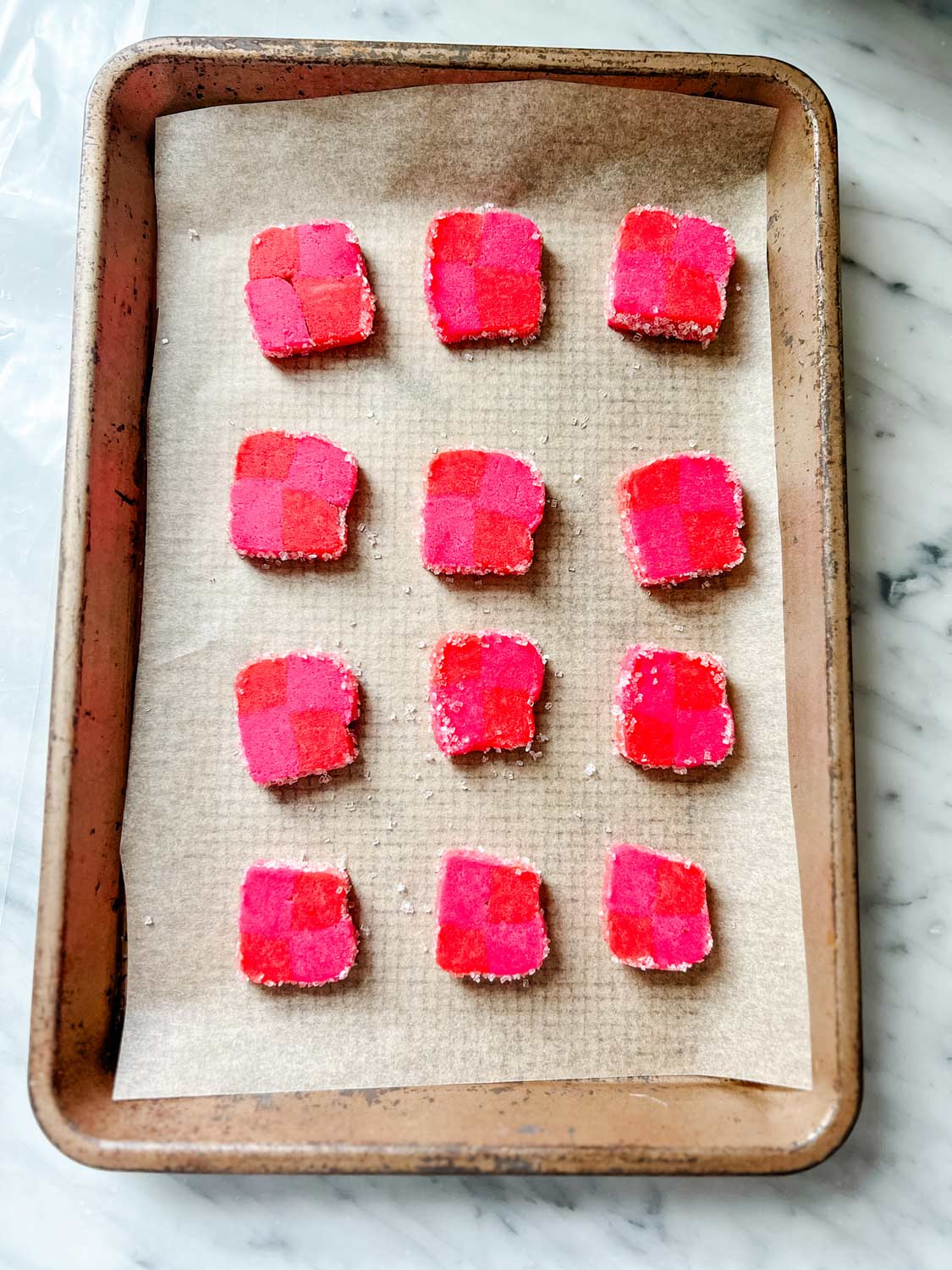 pink and red shortbread cookies on cookie sheet with parchment paper lined