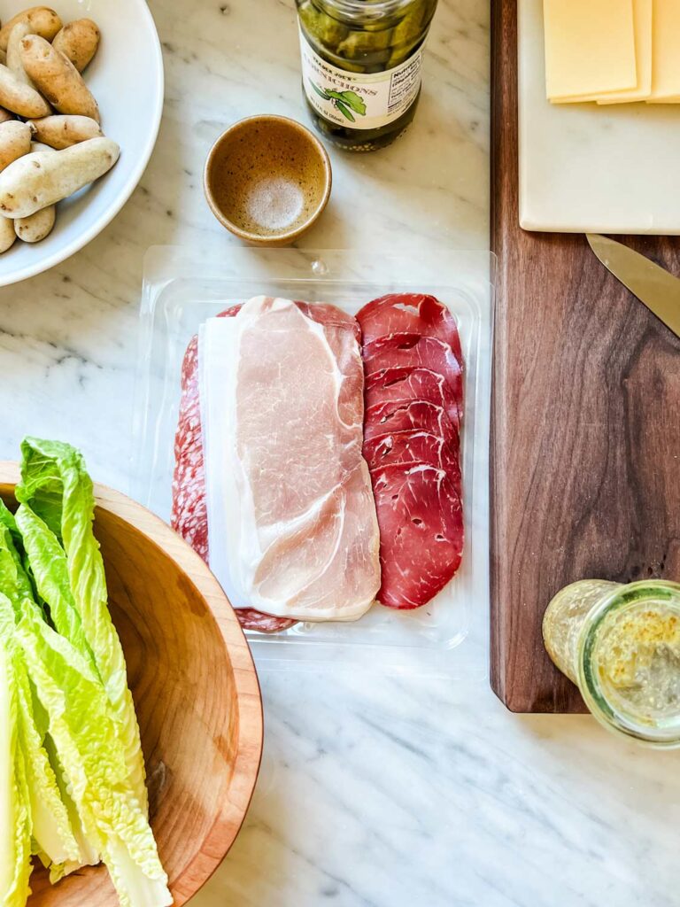 All the traditional things to serve with Raclette - salad, new potatoes, cured meats, cornichons, and Raclette cheese.