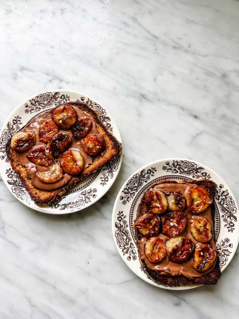 Caramelized banana and chocolate tartines on small plates ready to be served for breakfast.