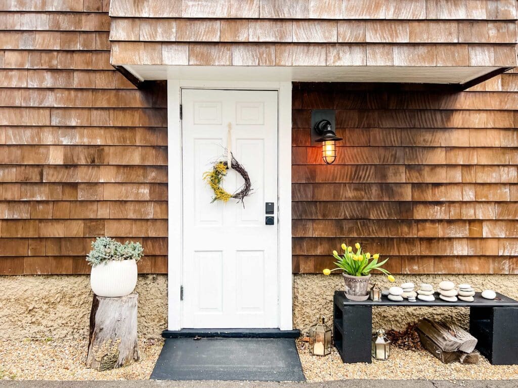 Make an Easy Spring Wreath with Mimosa Flowers cottage style house with white door black bench, yellow tulips 
