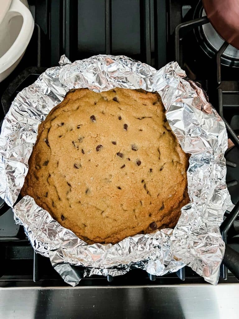 Foil is placed around the edges of a skillet chocolate chip cookie to keep the edges from burning while the center bakes to perfection.