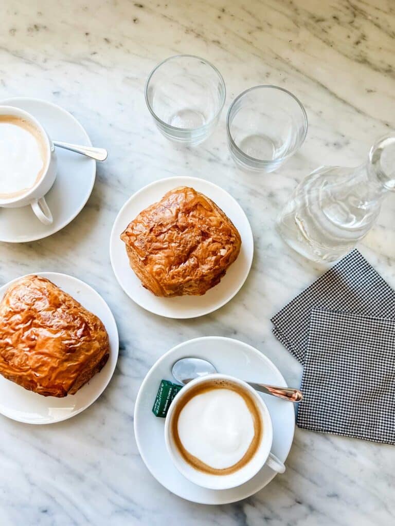Cremé coffee and croissants are served on white Apilco cups and saucers and small plates.