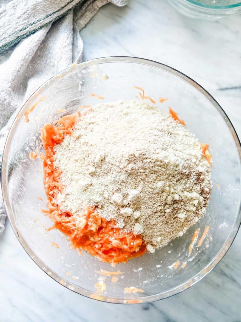 Almond flour with spices is being mixed with shredded carrots.