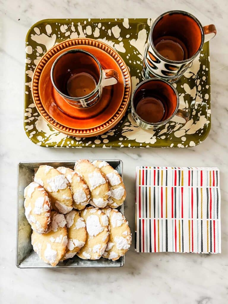 Lemon crinkle cookies sit next to a tray of coffee cups and colorful napkins ready to serve.