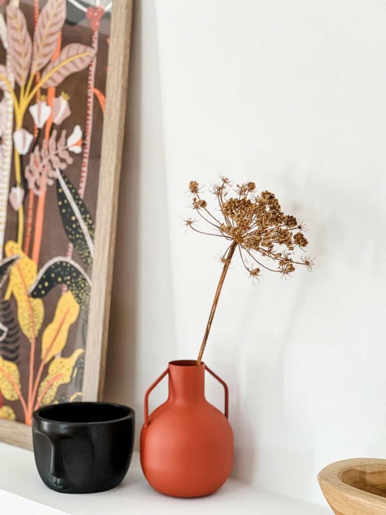 A small terra cotta pot is filled with dried flowers on the room shelf of this Airbnb in Provence, France.