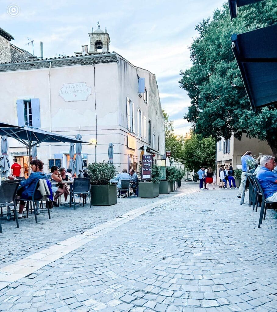 Sidewalk cafes line the main cobblestone street in the small village of Grignan, France.