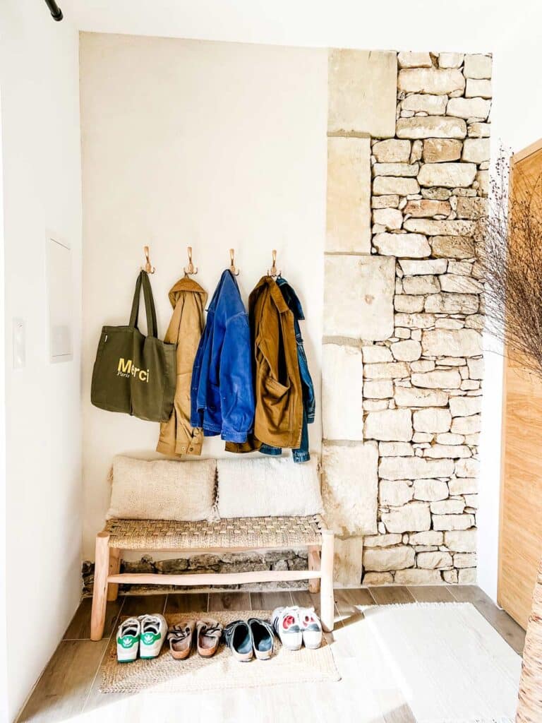 An artisan bench, hooks for coats, and a place for shoes are in the entryway of this Provence Airbnb.