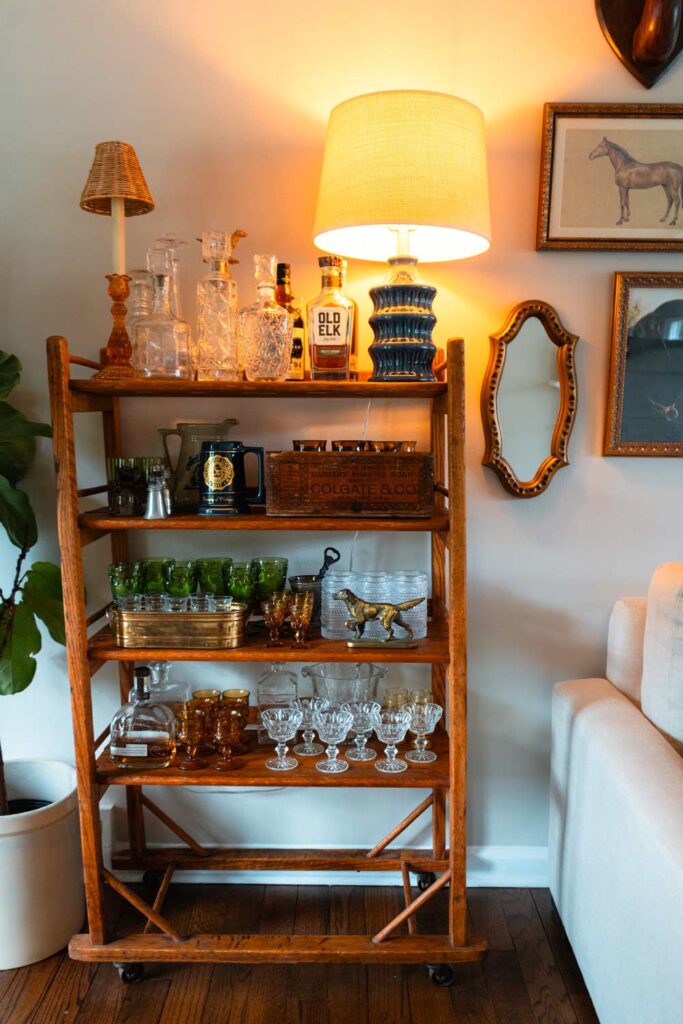 A vintage shelf is filled with glassware and other thrift store finds.