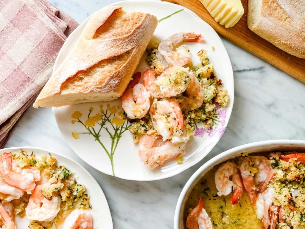 Ina Gareten's shrimp scampi is served on small plates with crusty bread and French salted butter. Checkered linen pink napkins are next to the plates.
