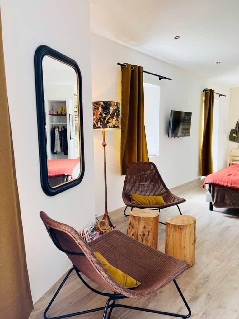 Two chairs, stools, and a lamp are the main features in the sitting area of this Airbnb in France.