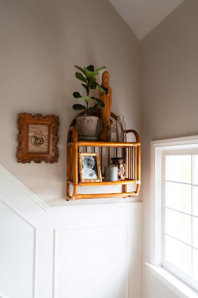 A vintage wall shelf hangs by in window in a beautiful stairwell.