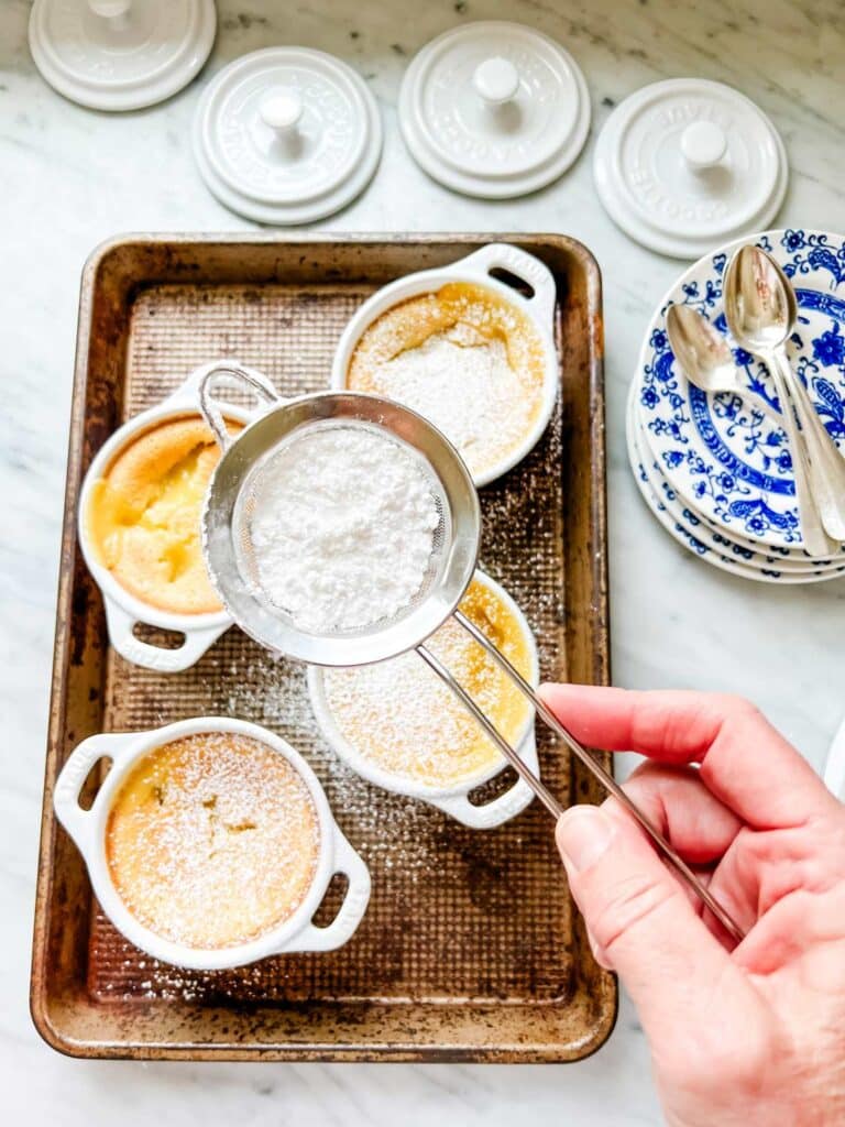 The baked lemon pudding is being dusted with powdered sugar.