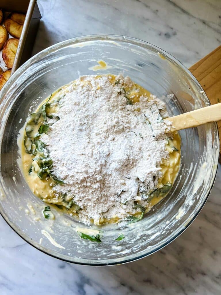 Flour, baking soda, salt, pepper, and basil are mixed into the batter of a potato basil frittata.