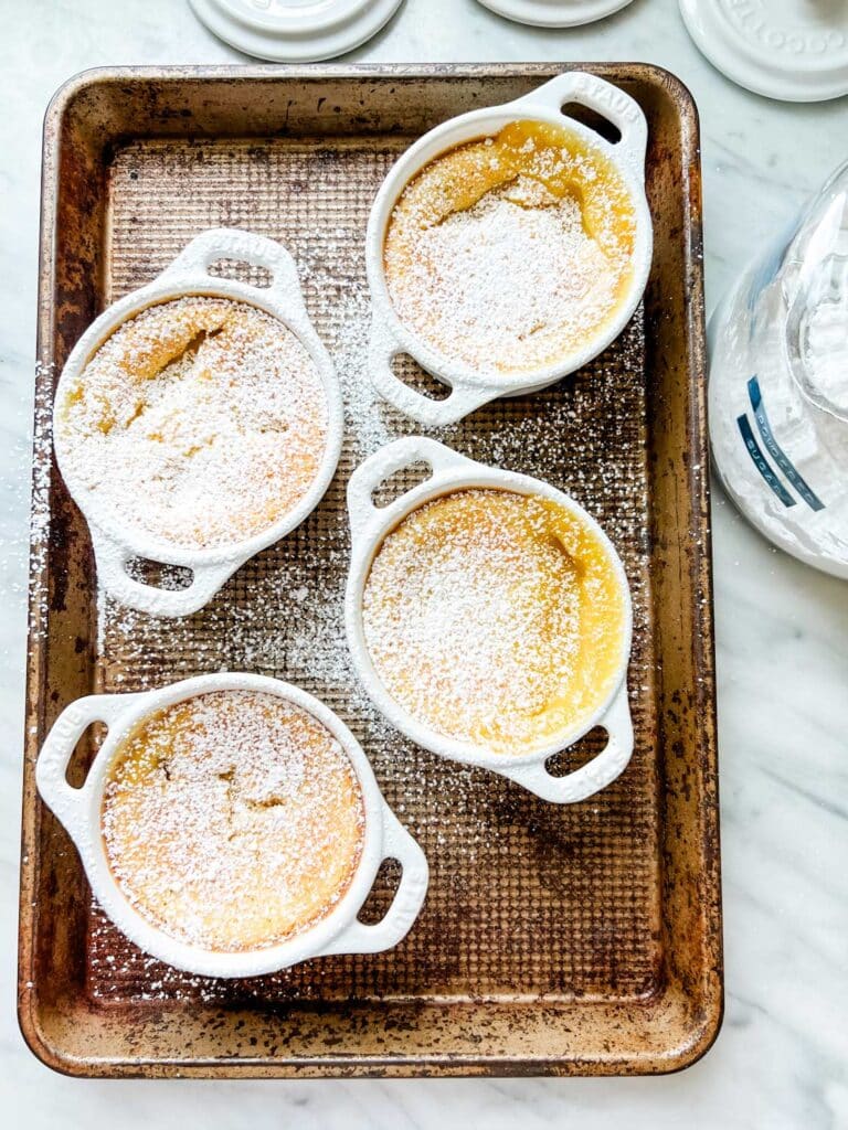 Lemon pudding dusted with powdered sugar is on a baking sheet.