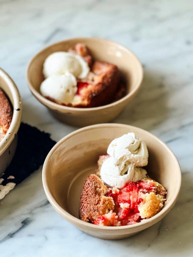 Two bowls of strawberry spoon caked served with scoops of vanilla ice cream.