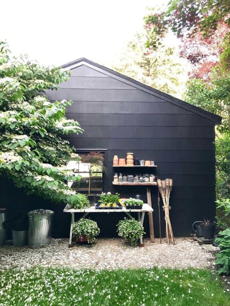 A potting bench and shelves with various clay pots make great use of space on the back side of a garage.