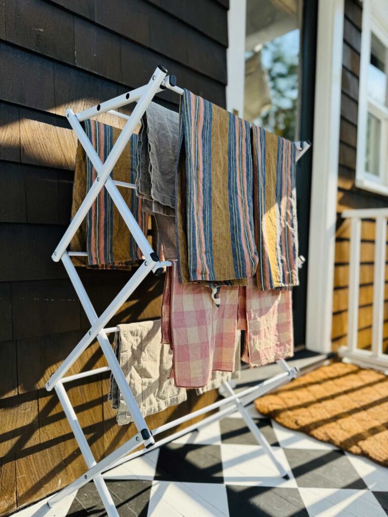 home linens like dish towels,  and napkins on dryong rack on black and white porch.