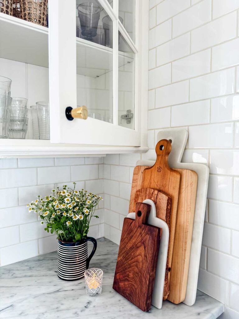 wood cutting boards, marble boards against white subway tiel, black and white pitcher with tiny daisies. 