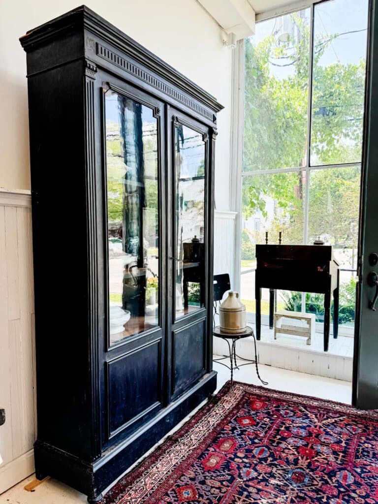 black glass cabinet on red rug with pattern