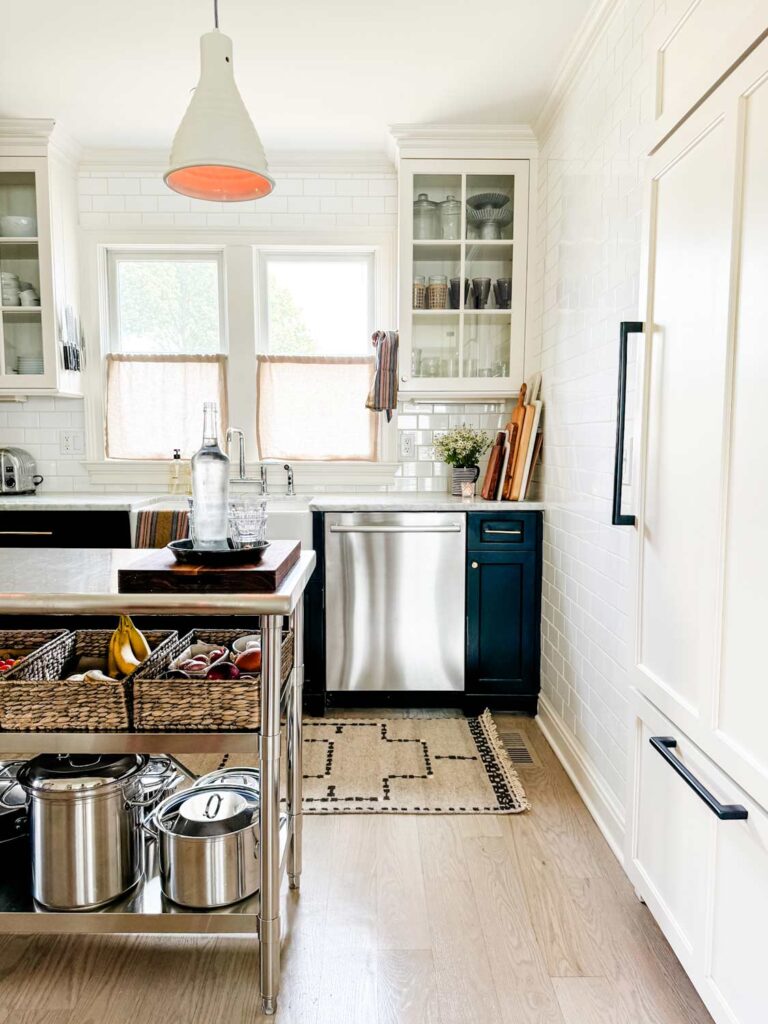 Cermaic pendant above stainless kitchen island with basket and pots.