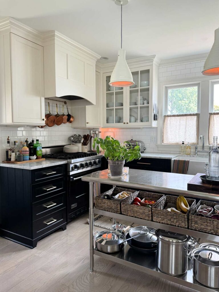 black base cabinets, stainless kitchen island, copper pots, basil plant.