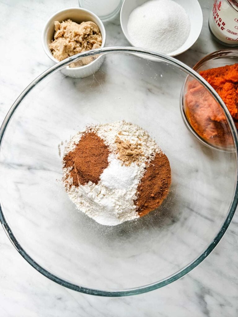 The dry ingredients for pumpkin spice muffins have been added to a large glass bowl.