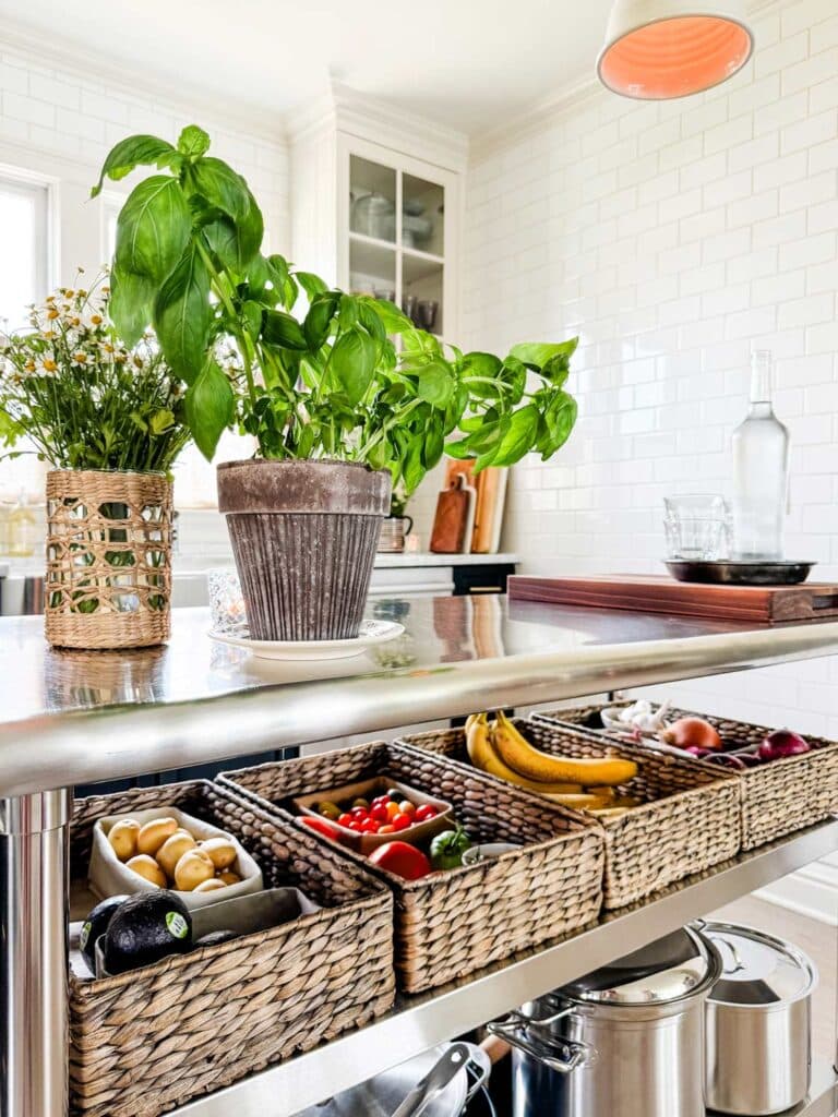 kitchen island with baksets, basil plant., vase of flowers.