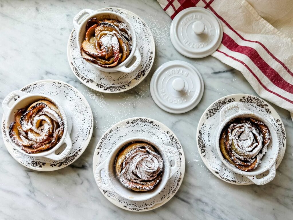 Puff pastry apple rose with brown butter, sugar, and cinnamon are in mini Staub cocottes.