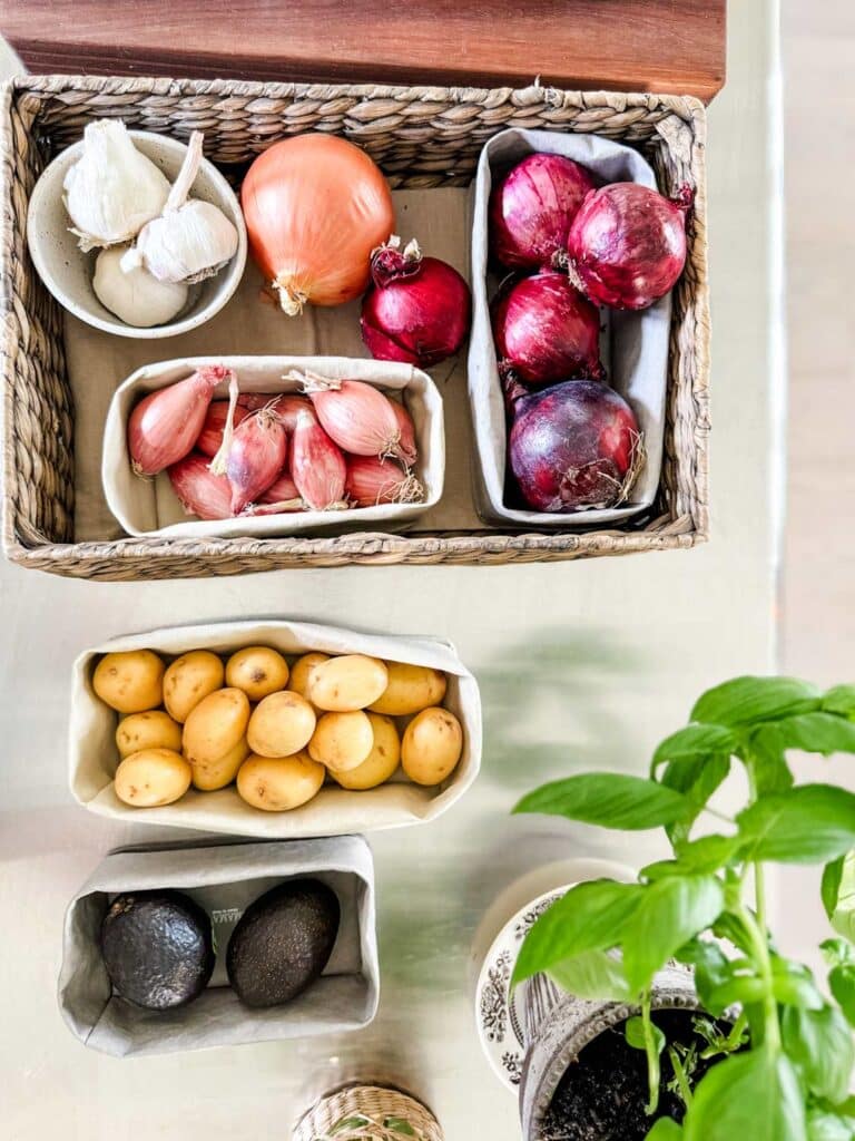 basket with onions, shallots, potatoes, avocados. 