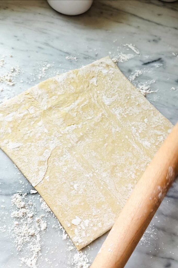 A puff pastry sheet is on a lightly floured surface and is ready to be rolled out to make puff pastry apple roses.